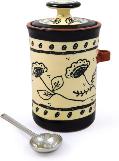Ceramic container with floral designs and a ladle on a white background