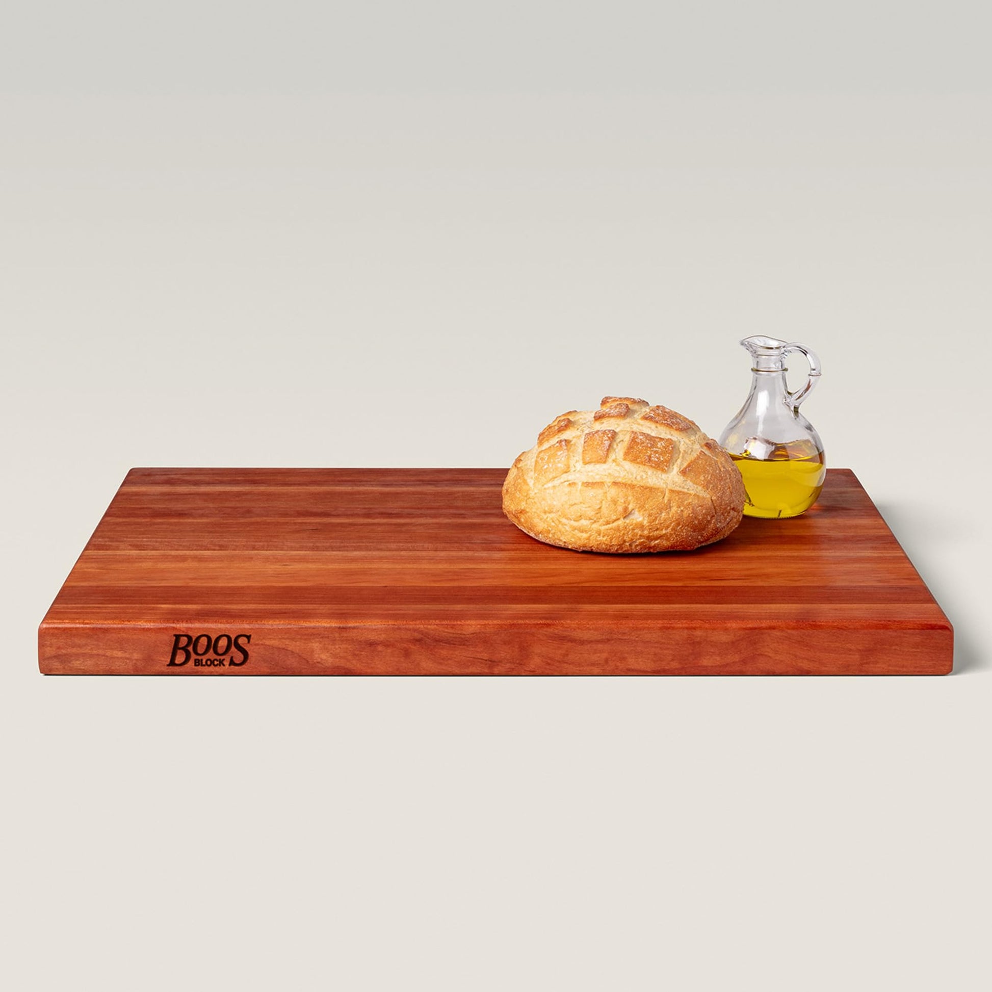 Wooden cutting board with bread and oil bottle on a light gray background