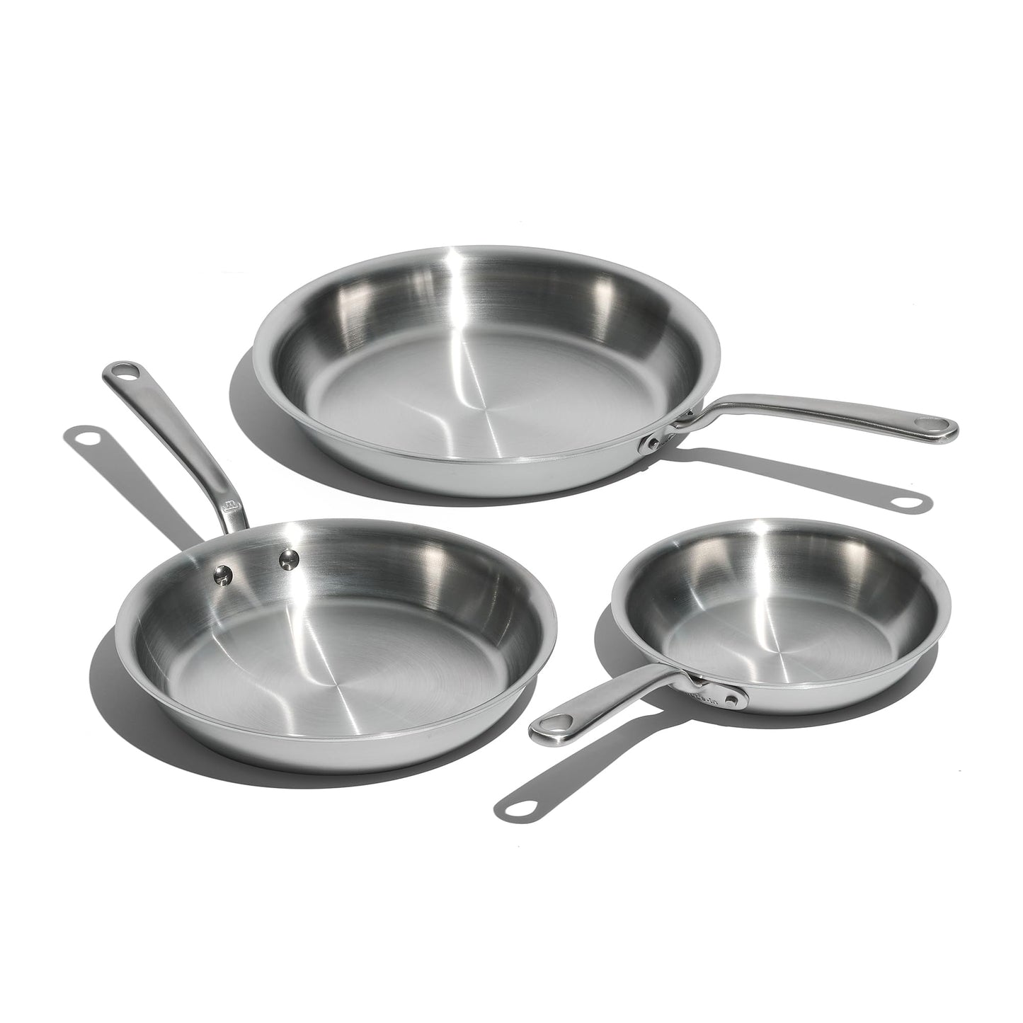 Set of four stainless steel frying pans on a white background