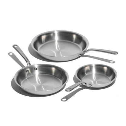 Set of four stainless steel frying pans on a white background