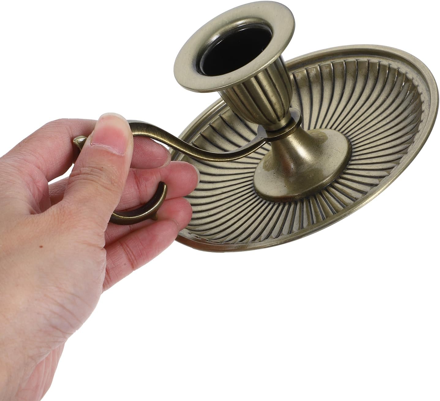 Hand holding a decorative brass candle holder against a white background