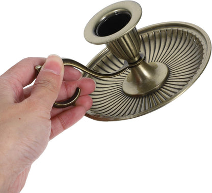 Hand holding a decorative brass candle holder against a white background