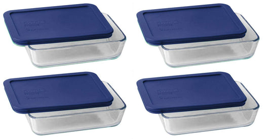Set of four glass food storage containers with blue lids on a white background