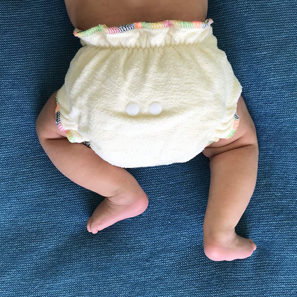 Baby wearing a yellow diaper with colorful trim on a blue fabric background