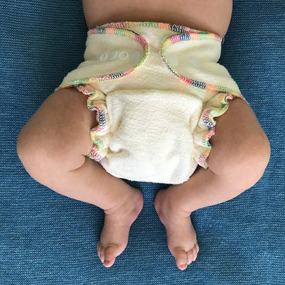 Baby wearing a colorful diaper on a blue textured surface