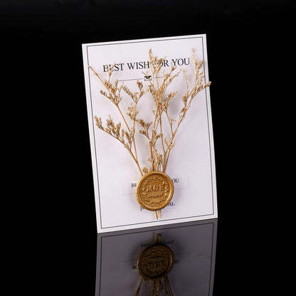 Decorative card with gold branch and medallion on a reflective surface