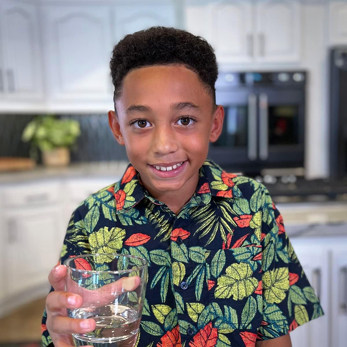 Child holding a glass of water in a kitchen