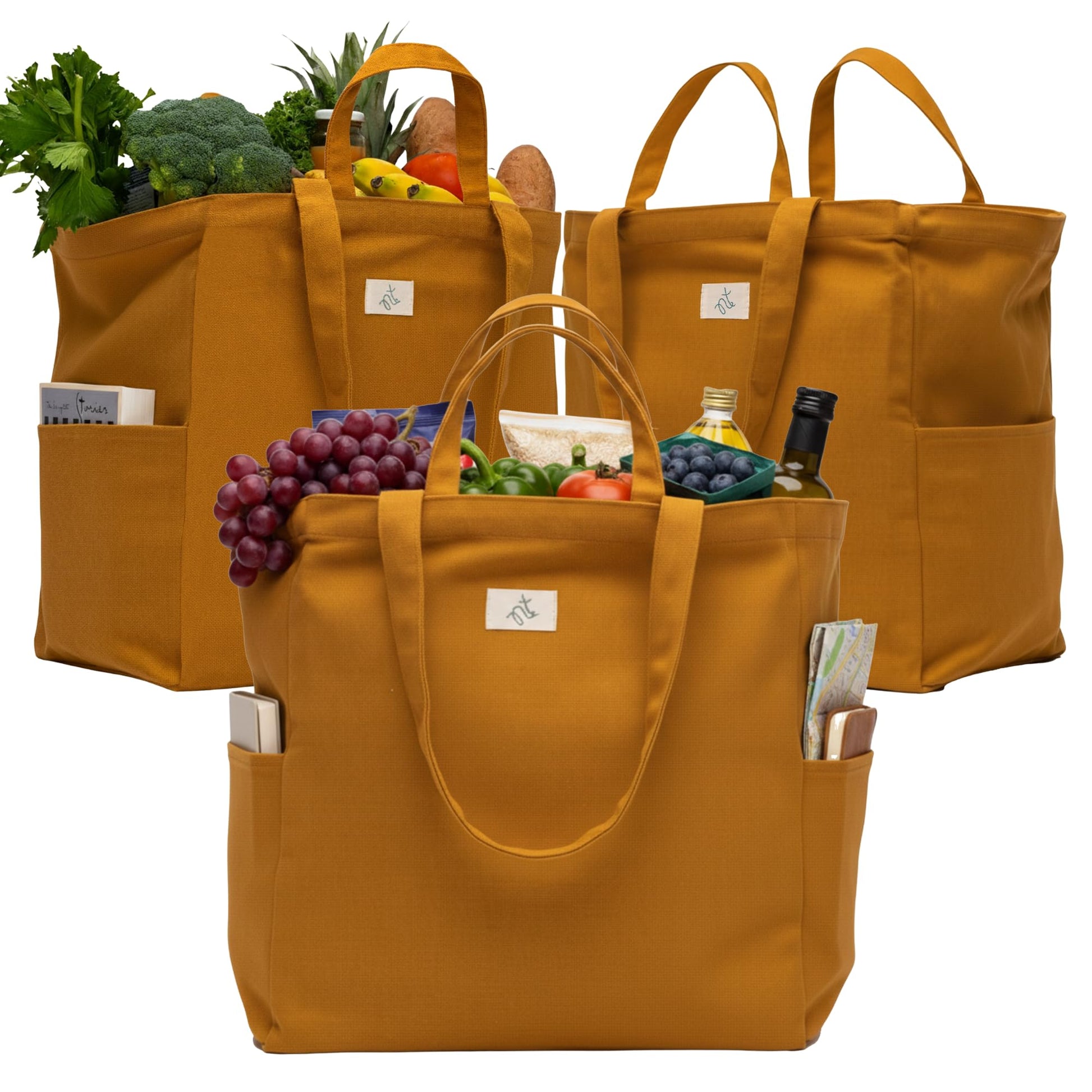 Three mustard yellow Nook theory cotton canvas grocery bags filled with groceries on a white background