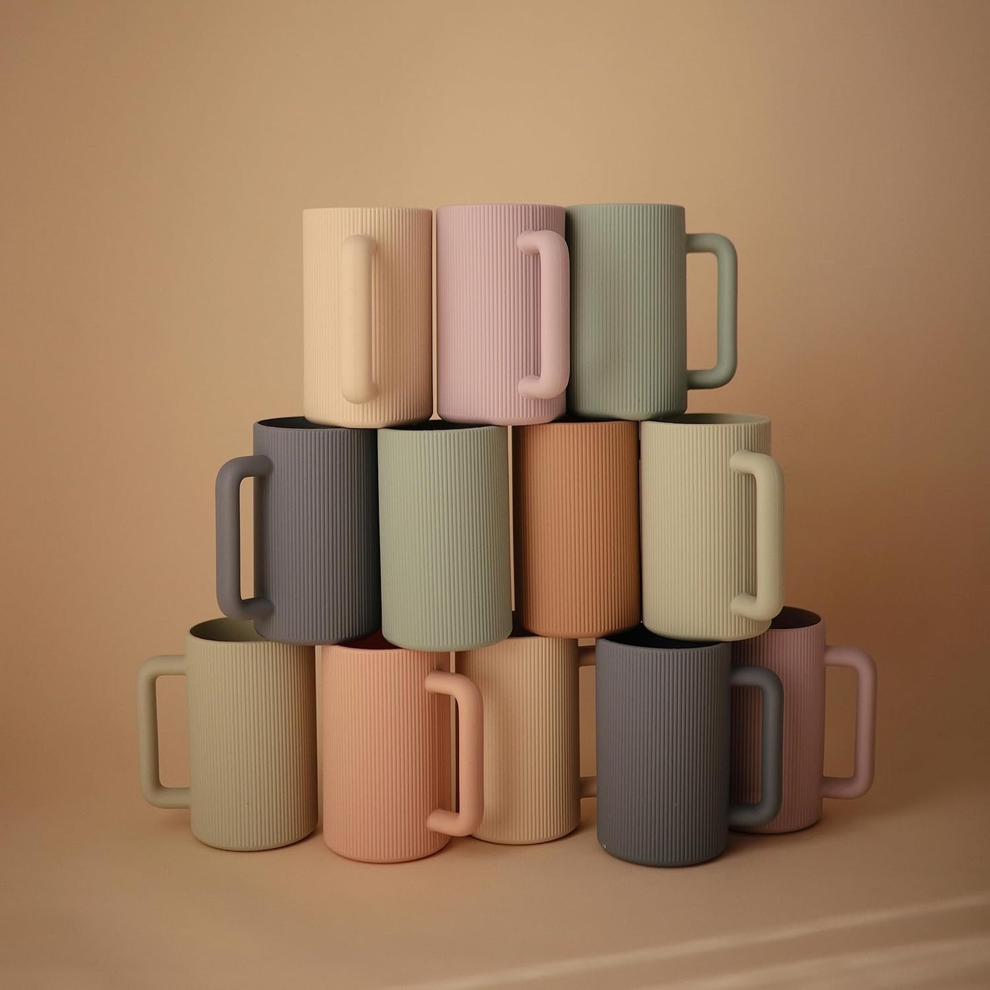 Stack of colorful mugs on a beige background