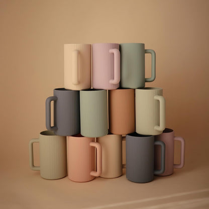 Stack of colorful mugs on a beige background