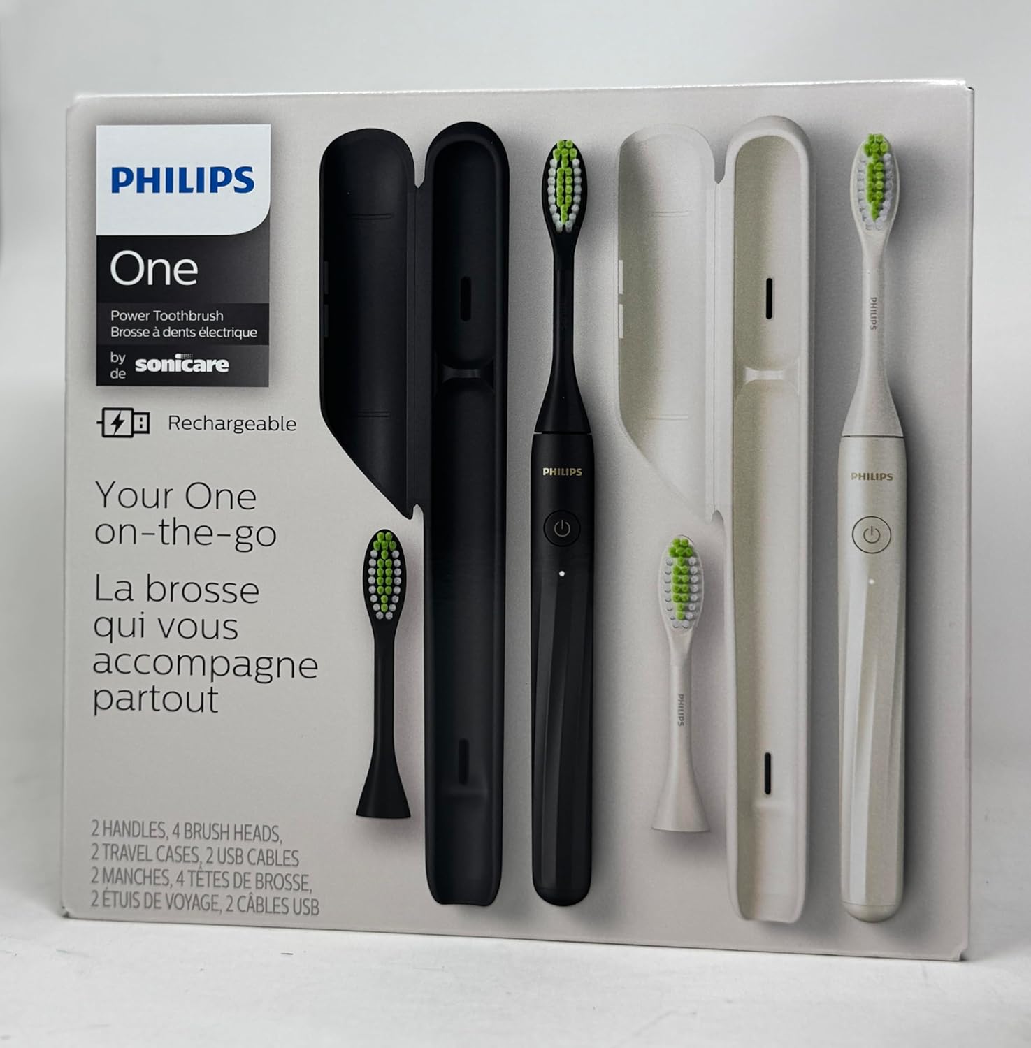 Philips One rechargeable toothbrush set in its original white retail packaging, featuring two black and two white toothbrushes with their charging cases and a travel case.