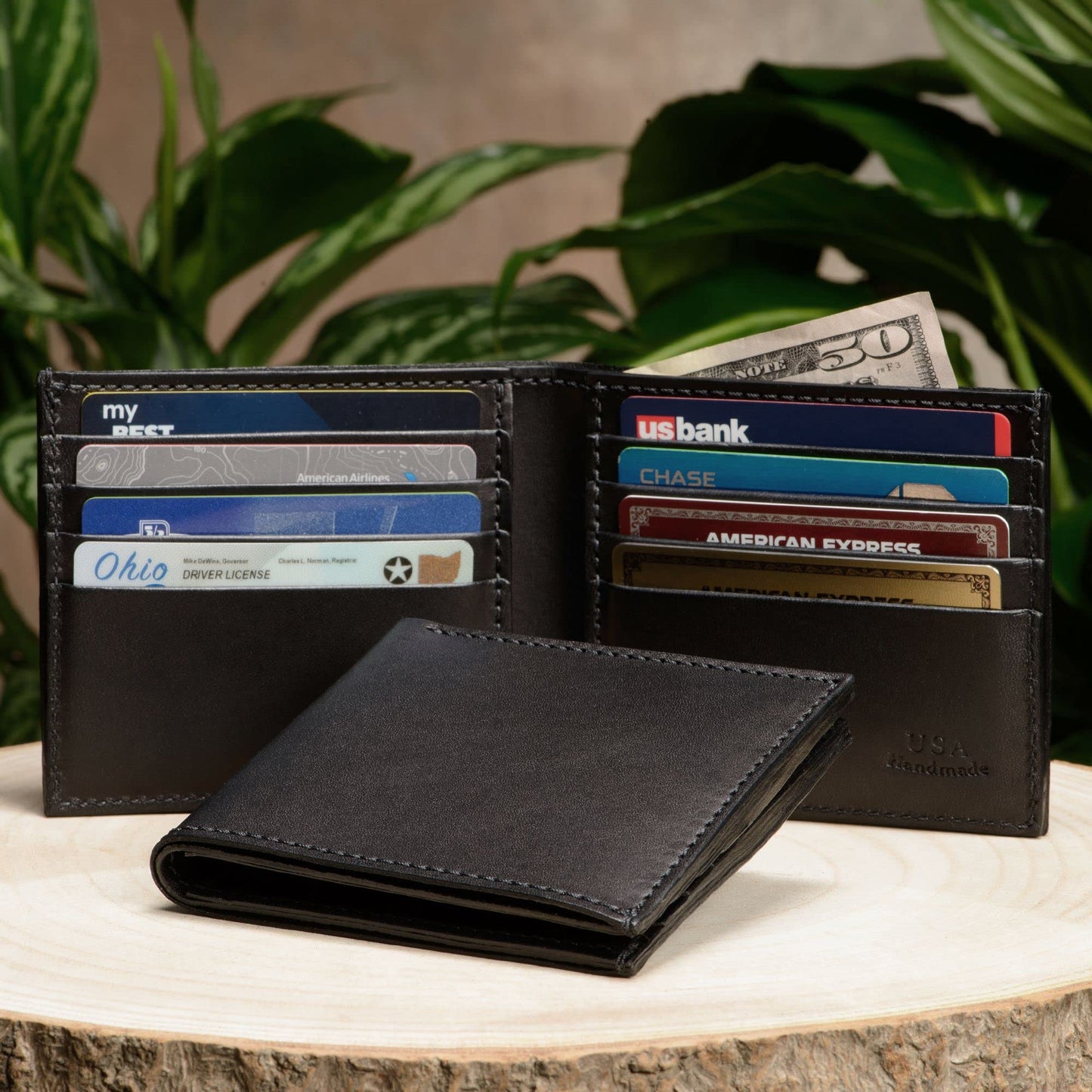 Black leather wallet with cards and money on a wooden surface with plants in the background