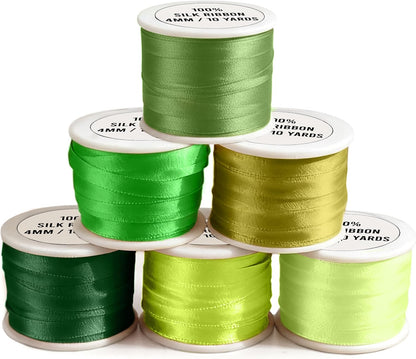 Set of green satin ribbon spools on a white background