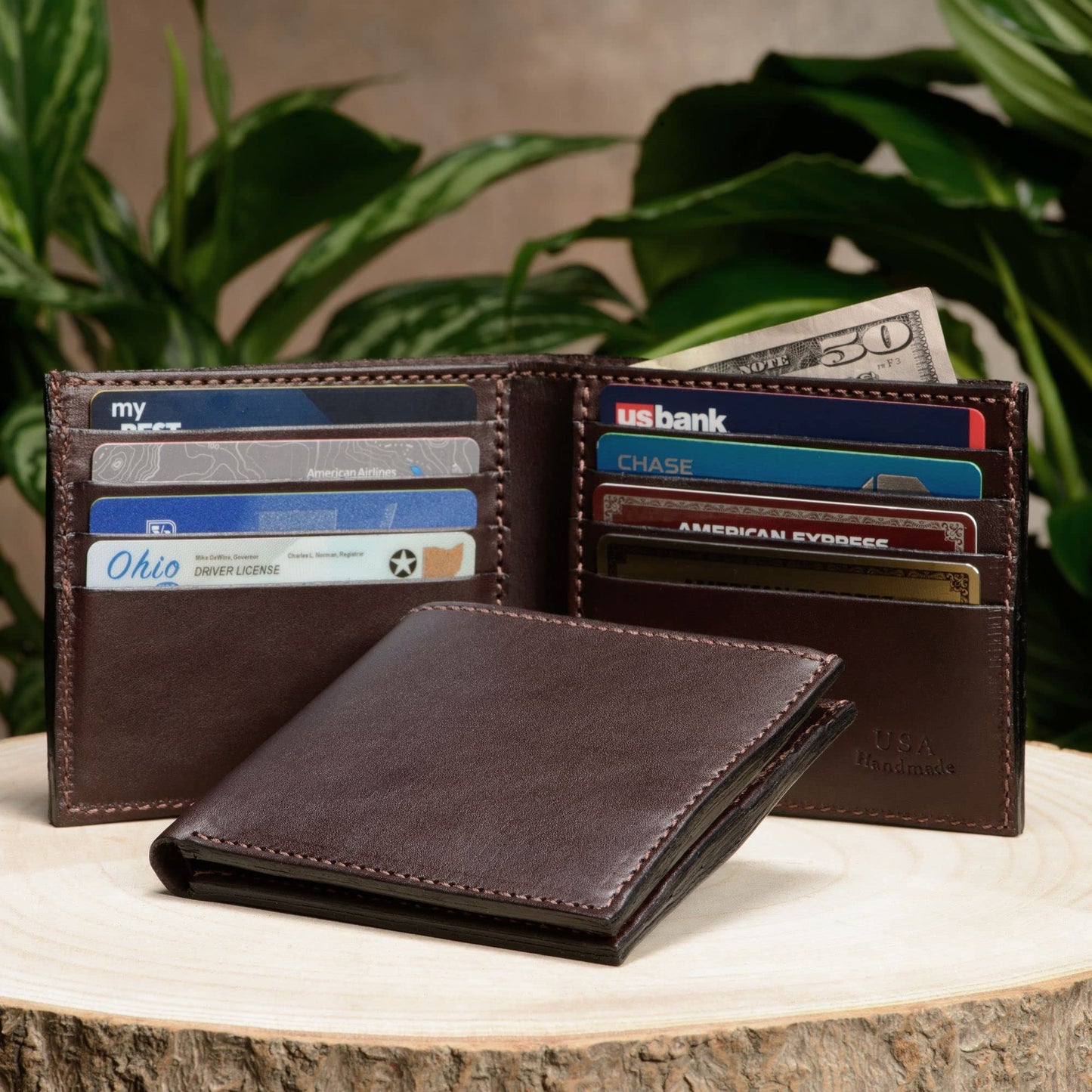 Brown leather wallet with cards and cash on a wooden surface with plants in the background