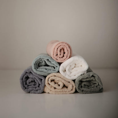 Stack of rolled-up towels in pastel colors on a neutral background