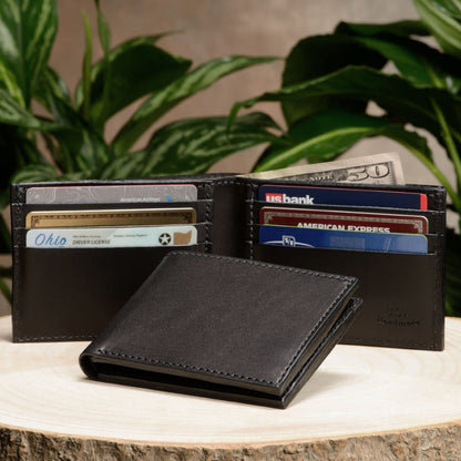 Black leather wallet with cards and money on a wooden surface with plants in the background