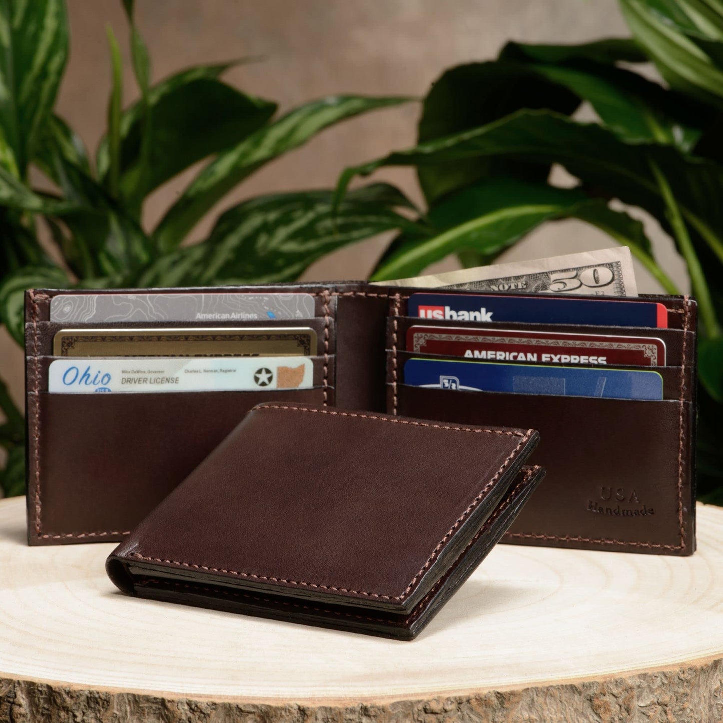 Brown leather wallet with cards and money on a wooden surface with plants in the background