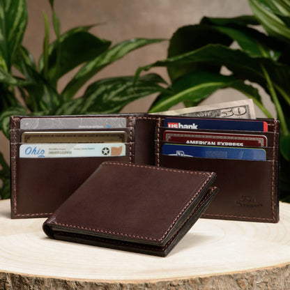 Brown leather wallet with cards and money on a wooden surface with plants in the background