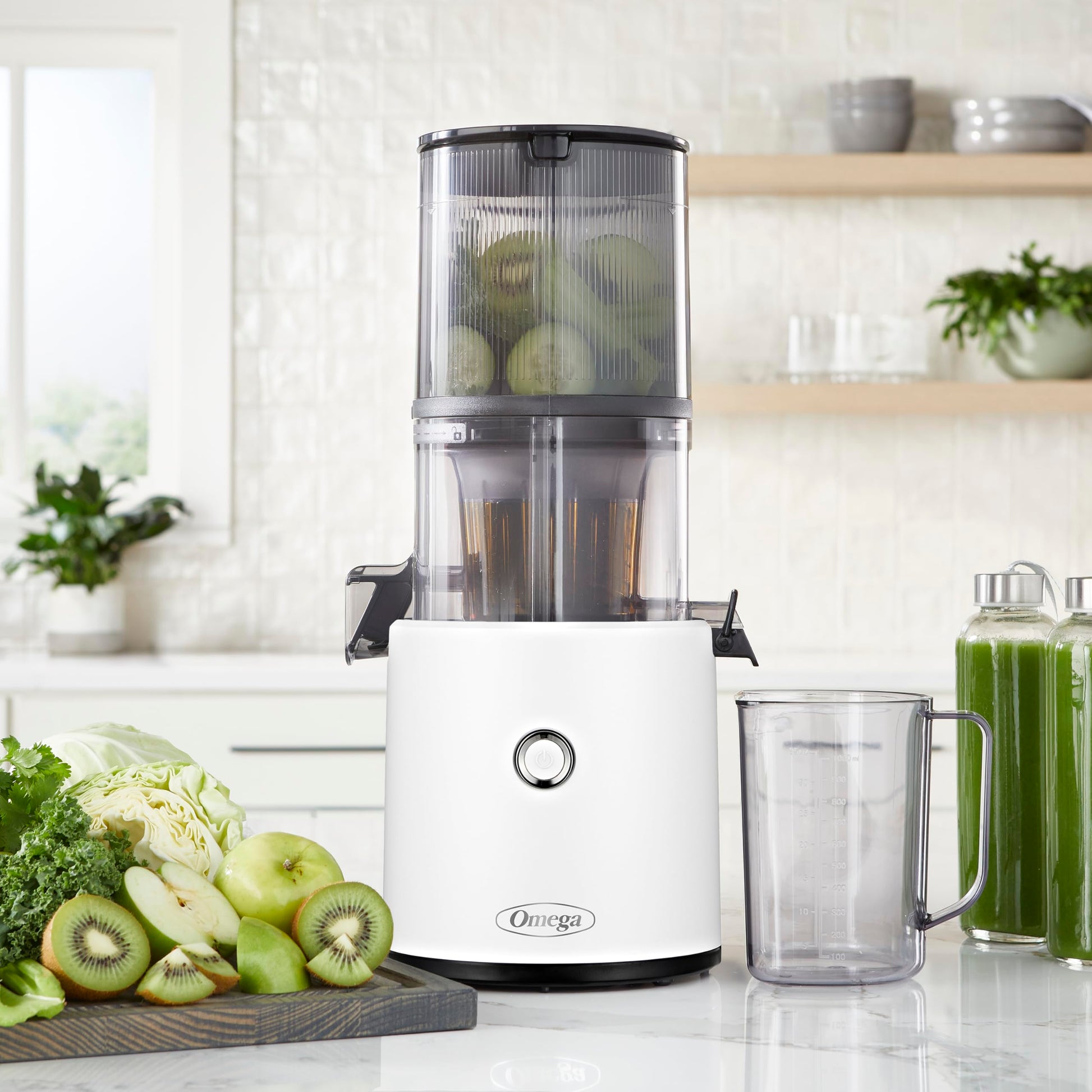 Omega juicer on a kitchen counter with ingredients and a glass of juice.