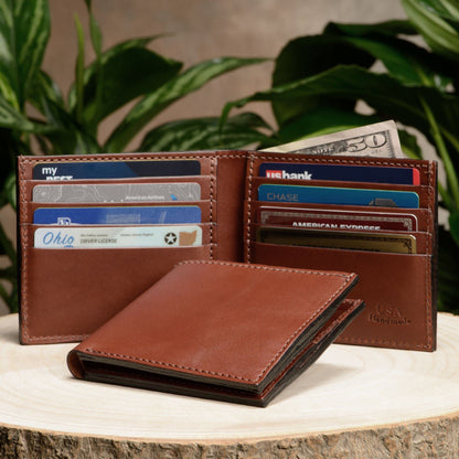 Brown leather wallet with cards and money on a wooden surface with plants in the background
