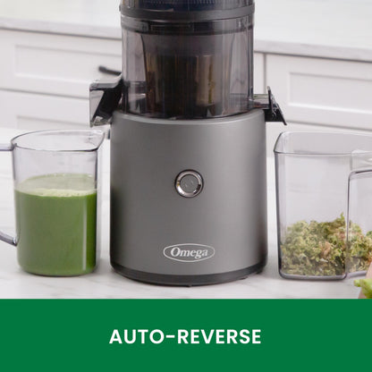 Omega juicer with green juice and ingredients on a white surface