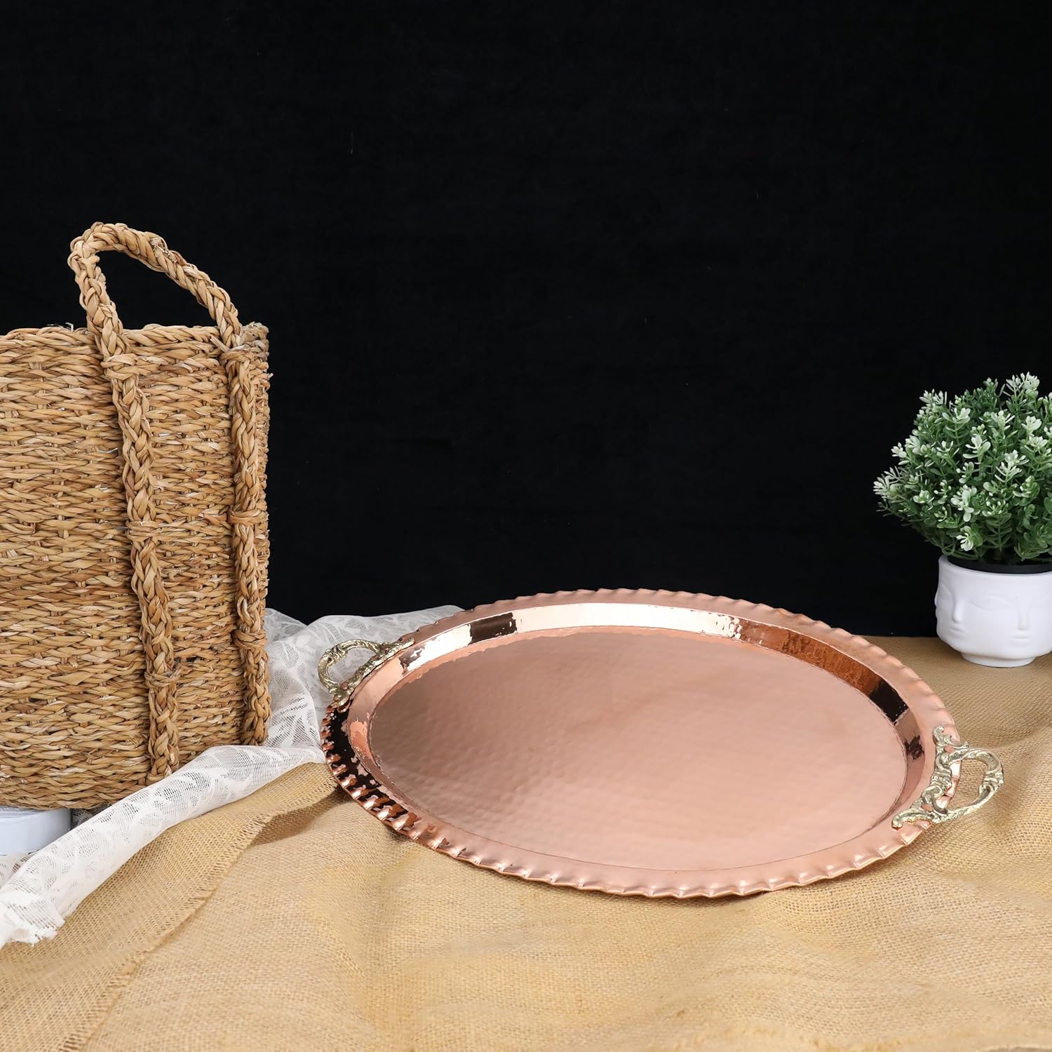 Copper tray on a table with a woven basket and plant in the background