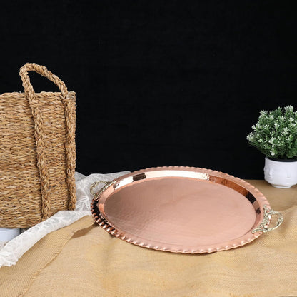 Copper tray on a table with a woven basket and plant in the background