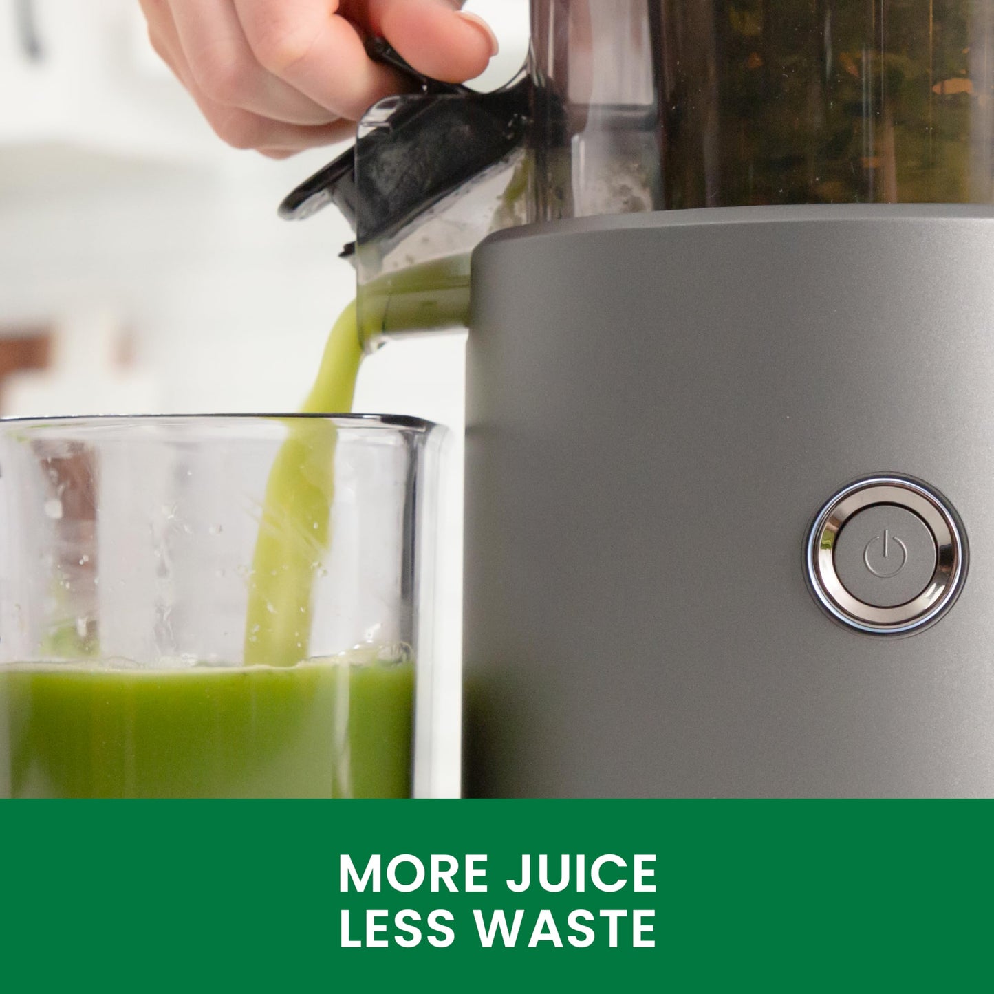Gray juicer with green juice being poured into a glass, featuring the text 'More Juice Less Waste'.