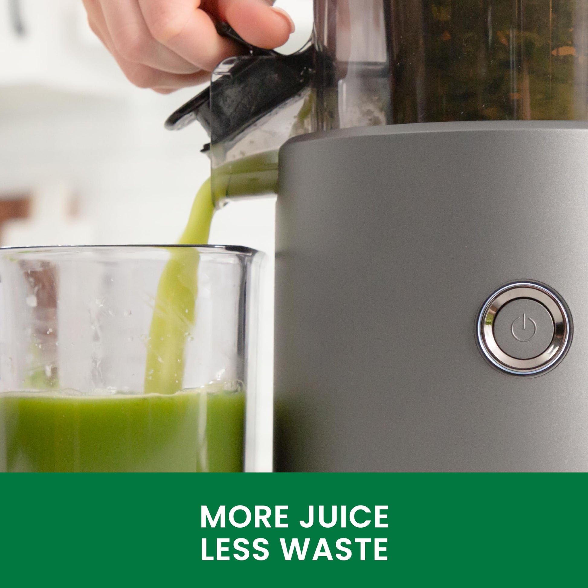 Gray juicer with green juice being poured into a glass, featuring the text 'More Juice Less Waste'.