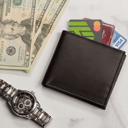 Black wallet with cards, dollar bills, and a watch on a marble surface