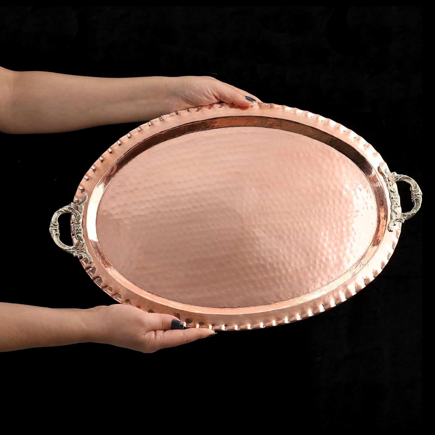 Copper tray held by a person against a black background