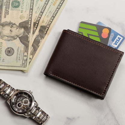 Brown leather wallet with cards, dollar bills, and a watch on a marble surface