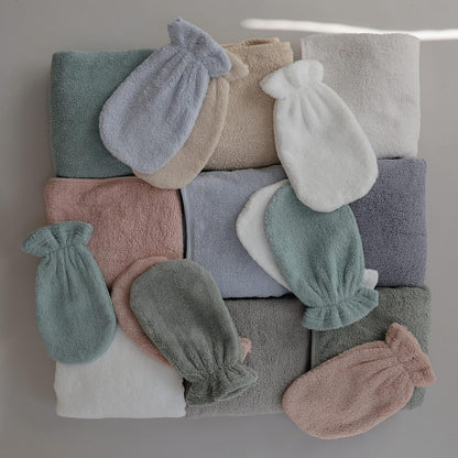 Stack of folded towels and baby booties in various colors on a neutral background