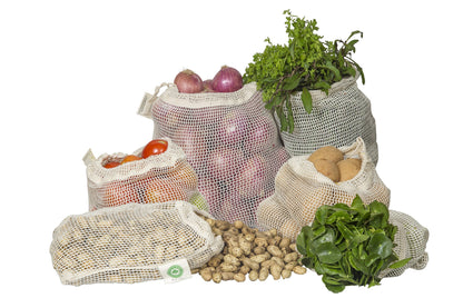 Set of reusable mesh grocery bags with vegetables and fruits on a white background