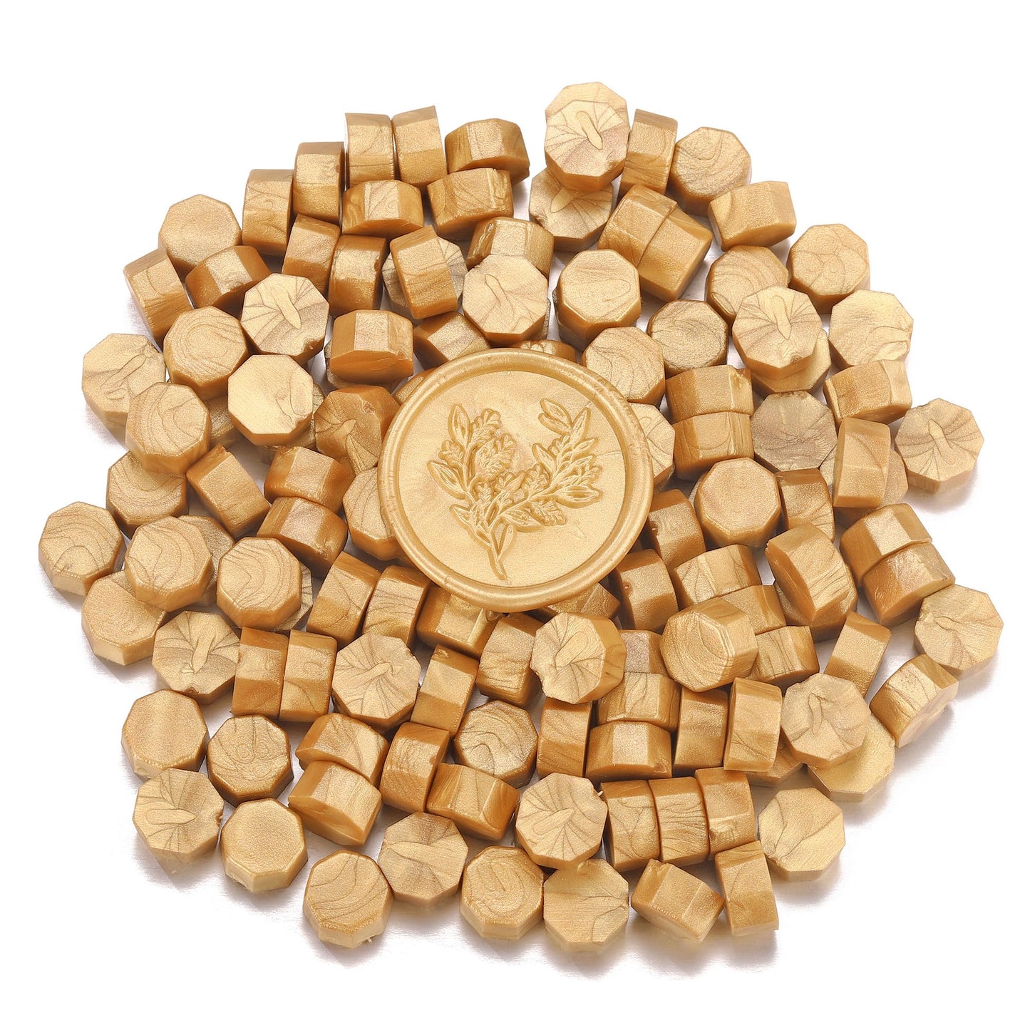 Gold sealing wax with a floral design surrounded by smaller sealing wax on a white background
