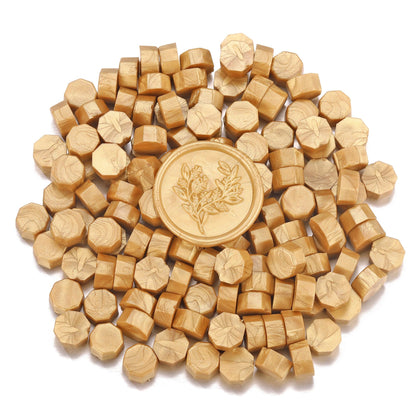 Gold sealing wax with a floral design surrounded by smaller sealing wax on a white background