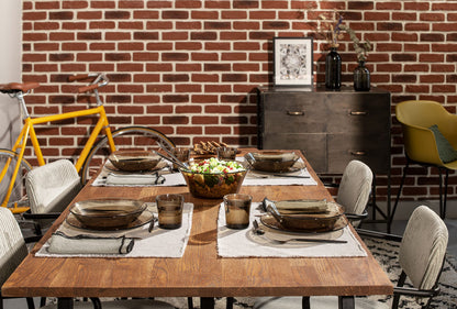 Dining table set with Duralex Lys Clear Glass Dinnerware Set, 18-Piece (Service for 6) against a brick wall with a bicycle and furniture in the background.