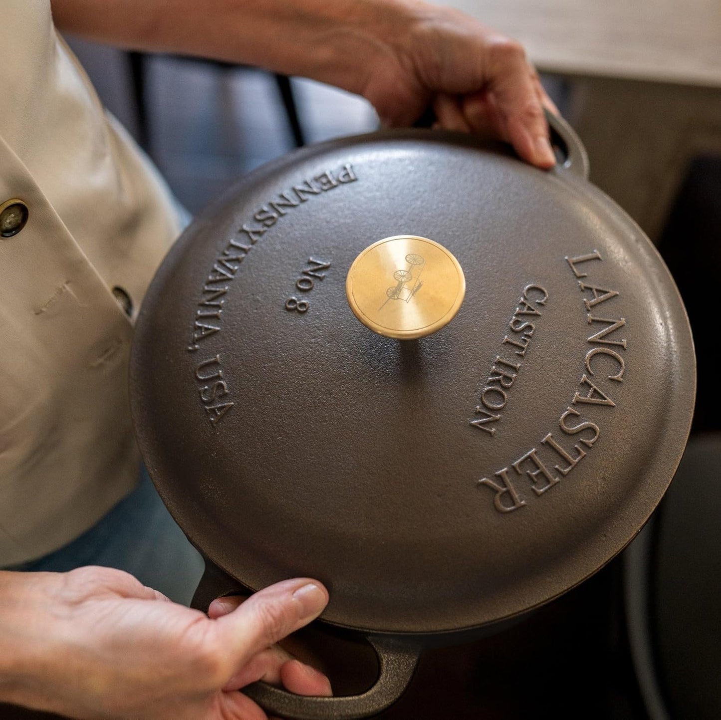 Person holding a cast iron skillet with 'Lancaster' branding