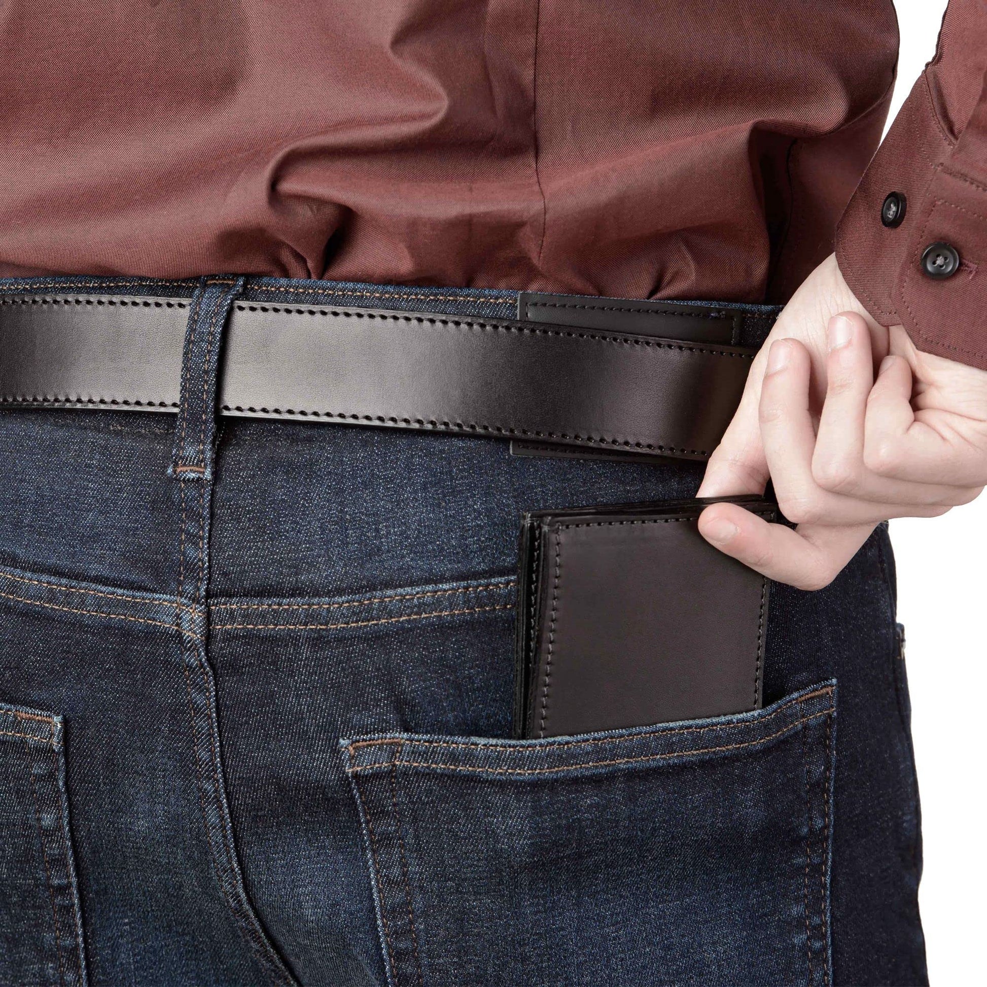 Person wearing dark blue jeans with a brown leather wallet in the pocket, holding a brown leather item.
