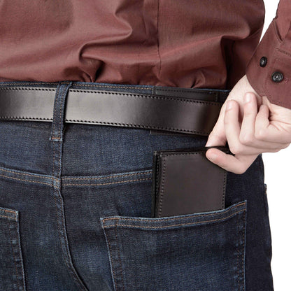 Person wearing dark blue jeans with a brown leather wallet in the pocket, holding a brown leather item.