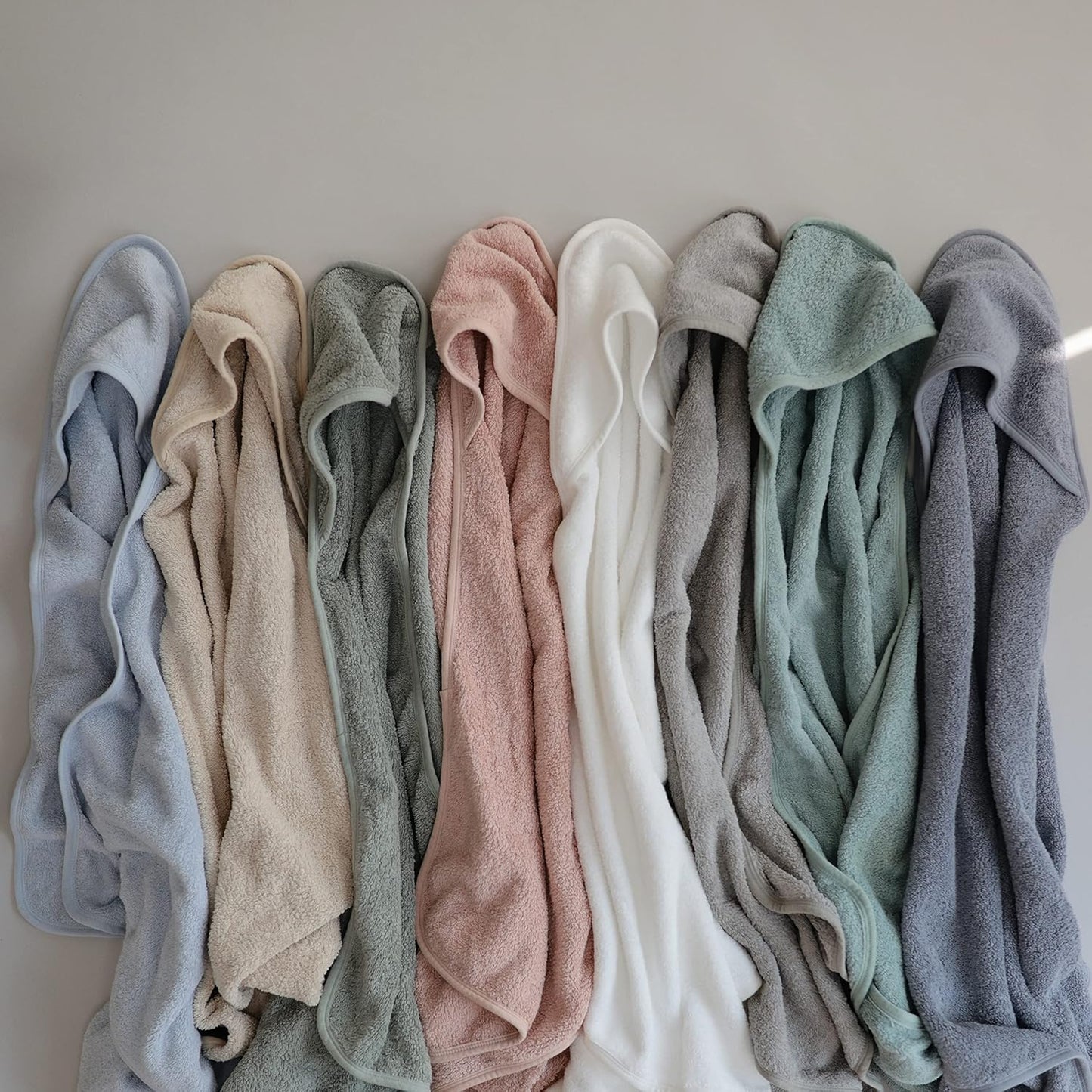 Row of folded towels in various colors on a neutral background