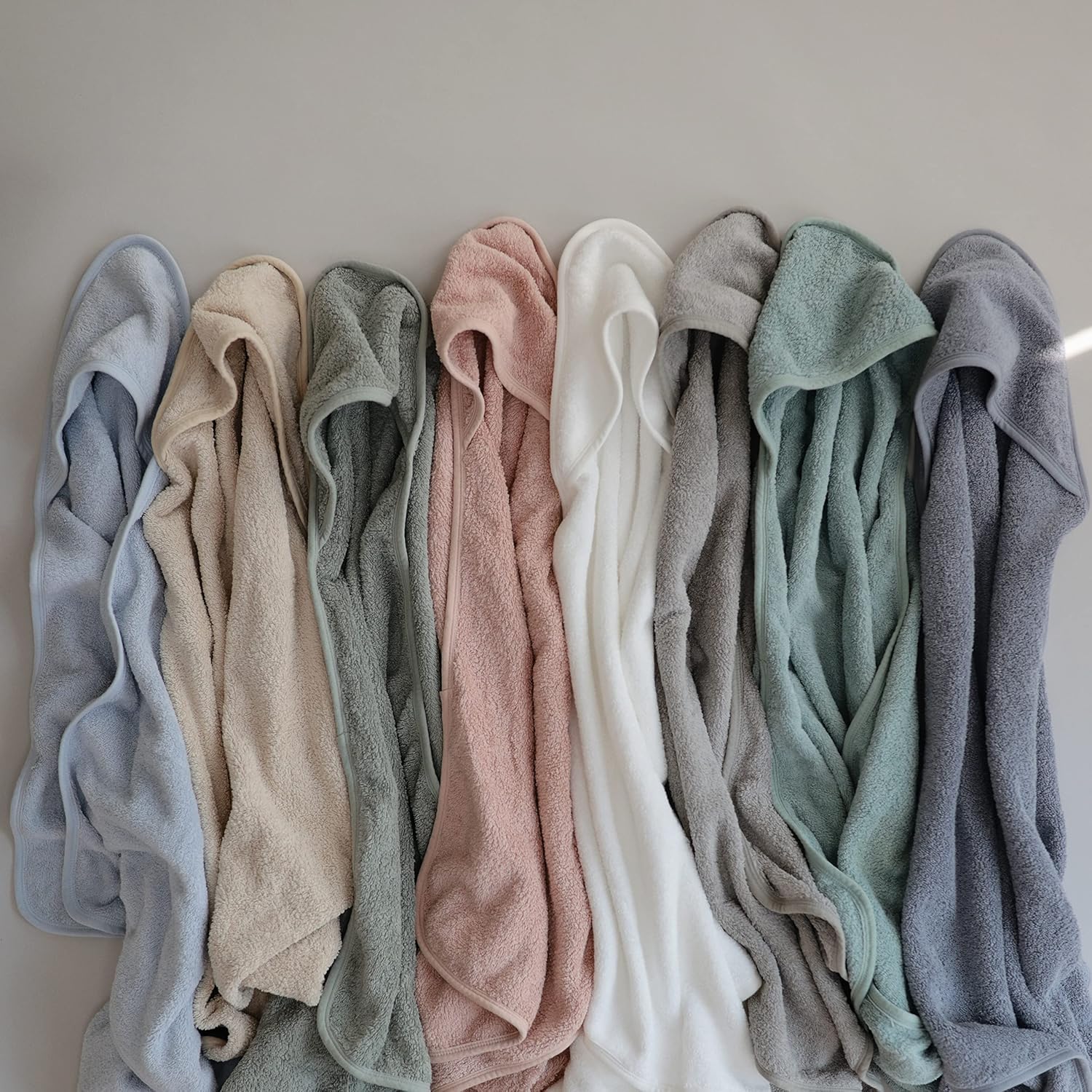 Row of folded towels in various colors on a neutral background