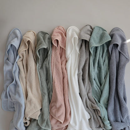 Row of folded towels in various colors on a neutral background
