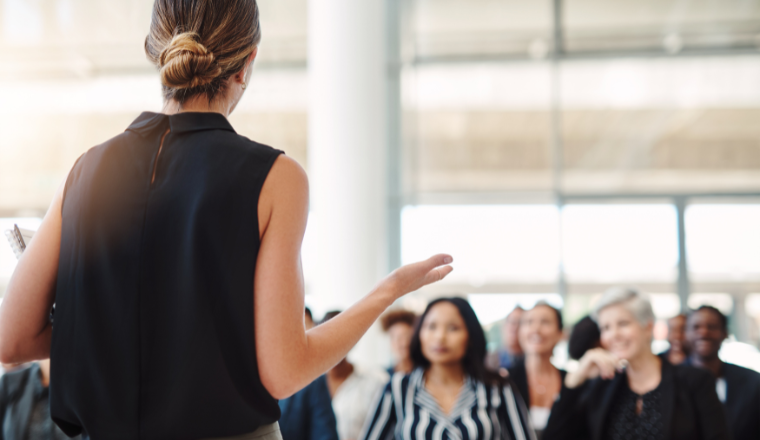 Woman giving a presentation to an audience in a conference room.