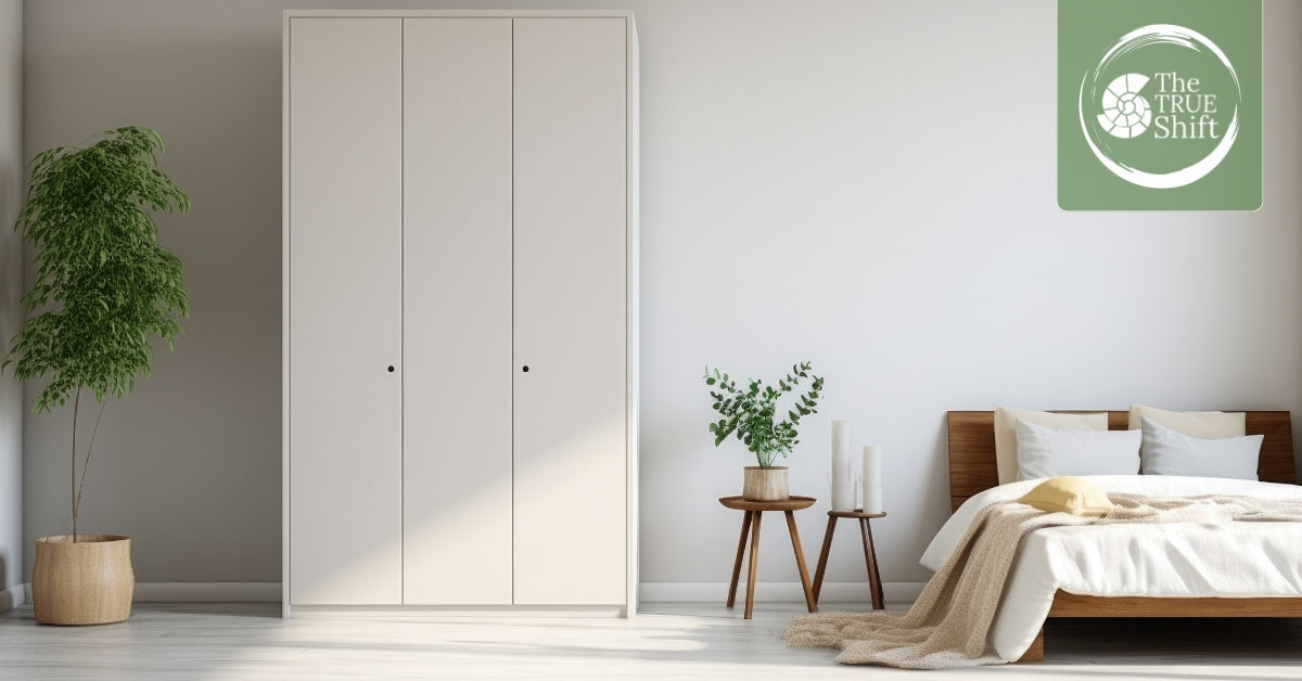 Modern bedroom with a wardrobe, bed, and small table with plants, featuring 'The True Shift' logo.